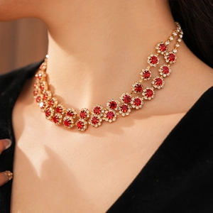 Detail of model wearing a double-layer flower necklace with red stones and gold finish