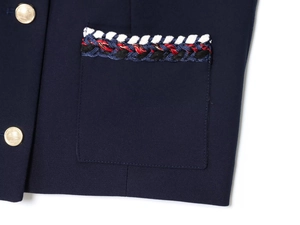 Détail d'un blazer bleu marine avec boutons dorés et garniture en tweed tricolore