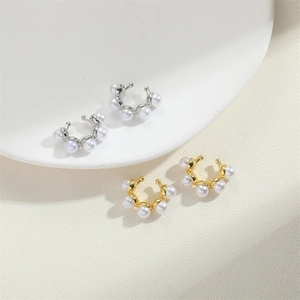 Minimalist C-shaped pearl ear cuffs in gold and silver finish on a textured background