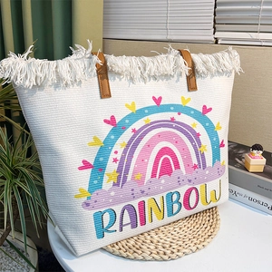 Detail of white woven tote bag with rainbow print, fringe decor and brown leather handles