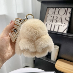 Detail of plush beige rabbit fur keychain attached to a luxury car key fob accessory