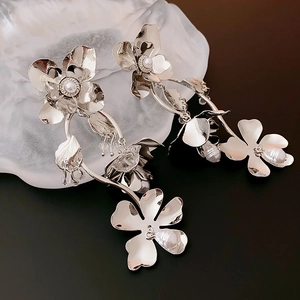 Close-up of floral silver earrings with integrated pearls and crystals on stone