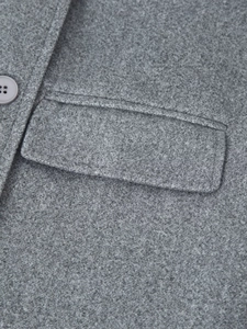 Macro di un cappotto grigio in lana che mostra la tasca a patta e il tessuto strutturato