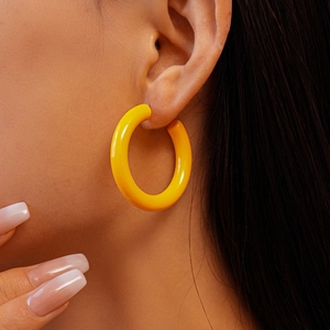 Gros plan d'un mannequin portant de grandes boucles d'oreilles créoles jaunes brillantes
