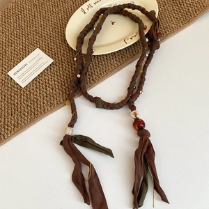Macro shot of ethnic beaded waist chain with amber resin beads and cotton tassels