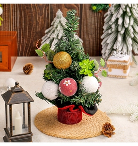 Detailed view of mini Christmas tree with red berries and golden ornaments on straw mat