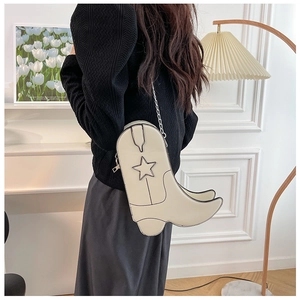 Detail view of cream boot-shaped crossbody bag with black trim and star pattern
