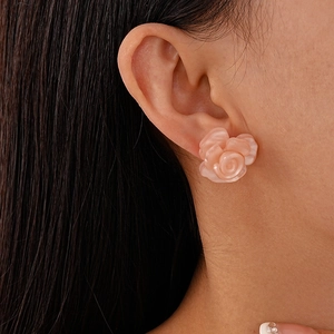 Close-up of elegant pink resin rose stud earring with pearlescent finish on model