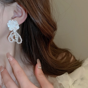 Détail de boucles d'oreilles fleur blanche avec triples créoles en perles