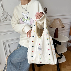 Detail of the high-quality canvas tote bag with vibrant floral embroidery and wide handles