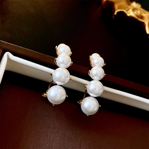 Macro detail of French vintage pearl crawler earrings on a golden metal base