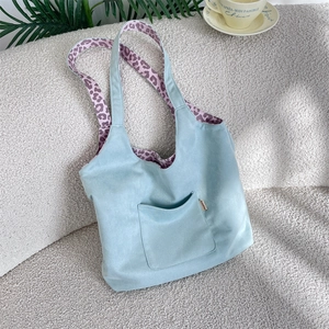 Detail of blue suede tote bag with leopard print lining and practical front pocket