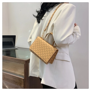 Detail of light tan crossbody bag with repeated M pattern print and elegant flap closure