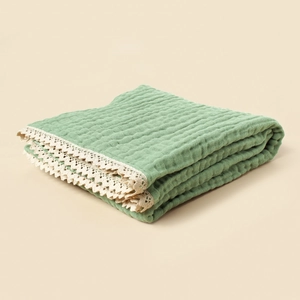 Detail of sage green waffle cotton baby blanket featuring delicate cream lace edging
