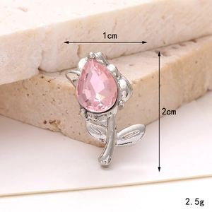 Macro shot of silver tulip shoe accessory with pink gemstone and dimension markings
