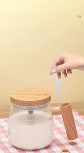Detail of detachable white whisk being held over a 400ml glass automatic stirring mug
