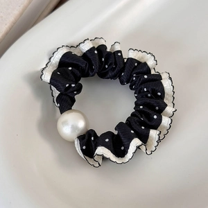 Detail of polka dot scrunchie with lace edge and white pearl on a ceramic plate