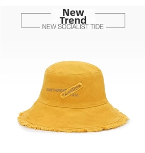 Detail of frayed edges and embroidery on a yellow cotton denim bucket hat for women