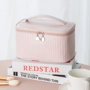 Pink PU leather makeup bag with vertical stripes and top handle in a lifestyle setting