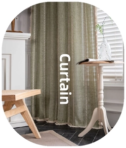 Detail of green linen curtain featuring white geometric embroidery and tassel fringe