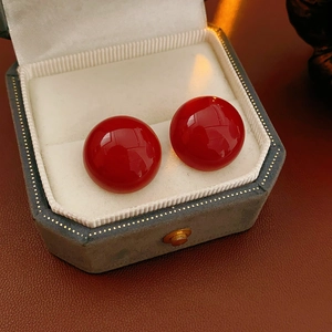 Orecchini a semicerchio rosso scuro in un portagioie esagonale vintage su pelle