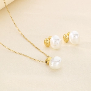 Detailed set of gold necklace and earrings with white shell inlays on beige background