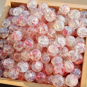 Detailed close-up of pink and red gold-foil glass beads for DIY jewelry making in a tray