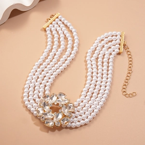 Gros plan d'un collier de perles à cinq rangs avec fleur de cristal et métal doré poli