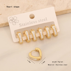 Close-up of golden stainless steel heart stud earrings with sparkling white crystals