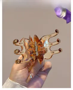 Detail of amber translucent butterfly hair claw clip held by hand with floral decor