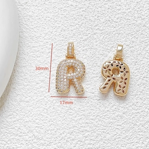 Macro view of gold letter R pendant with cubic zirconia and dimensions 30mm by 17mm