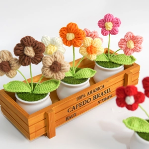 Detailed view of colorful crochet flower pots in a rustic branded wooden crate