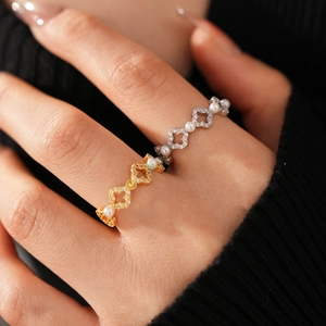 Détail de bagues trèfle en or 18k et argent avec perles et zircon sur les doigts