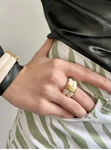 Close-up of gold and cream enamel ridged wide ring and matching bracelet on model