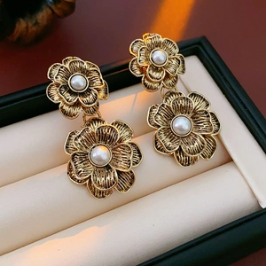 Close-up of vintage flower earrings with gold finish and white pearls in a jewelry box