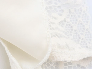 Detailaufnahme der cremefarbenen Spitze und des glatten Futters am eleganten Kleid