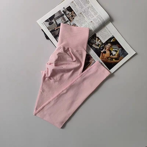 Detailed macro view of pink high-waisted yoga pants with ribbed compression waistband