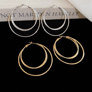 Detailed close-up of 18k gold and silver tiered hoop earrings with polished and textured finish