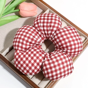 Detail of a large red and white gingham floral scrunchie on a wooden display tray