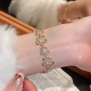 Macro shot of gold floral bracelet with sparkling zircon centers on a woman's wrist