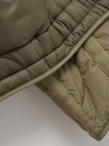 Detail of olive green quilted fabric with precise stitching and durable texture