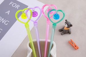 Detail of four colorful heart pendant pens in yellow purple pink and green transparent colors
