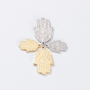 Macro detail of gold and silver Hamsa pendants with intricate engraved patterns