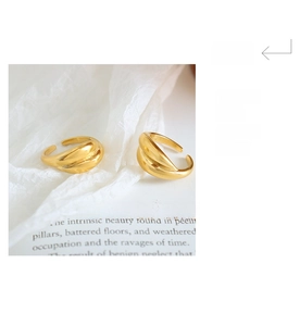 Detail of 18K gold-plated twisted croissant ring on elegant white organza and book