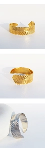 Dettaglio della trama a piuma del bracciale rigido aperto in finitura oro e argento