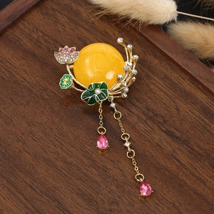 Detail of a Chinese style gourd brooch with yellow resin, enamel flowers and golden tassels