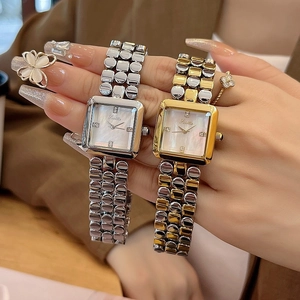 Close-up of elegant square mother-of-pearl dial watches with diamond markers and metal straps