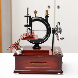Vintage sewing machine music box with red wood base and miniature scissors and fabric