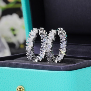 Macro shot of silver-tone hoop earrings with AAA zircons in a luxury jewelry box