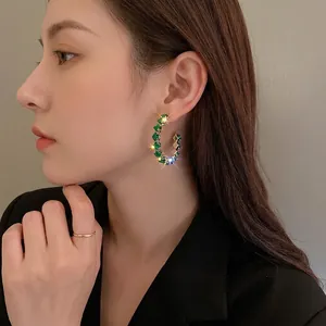 Emerald green square zircon C-shaped hoop earrings with gold plating on a female model
